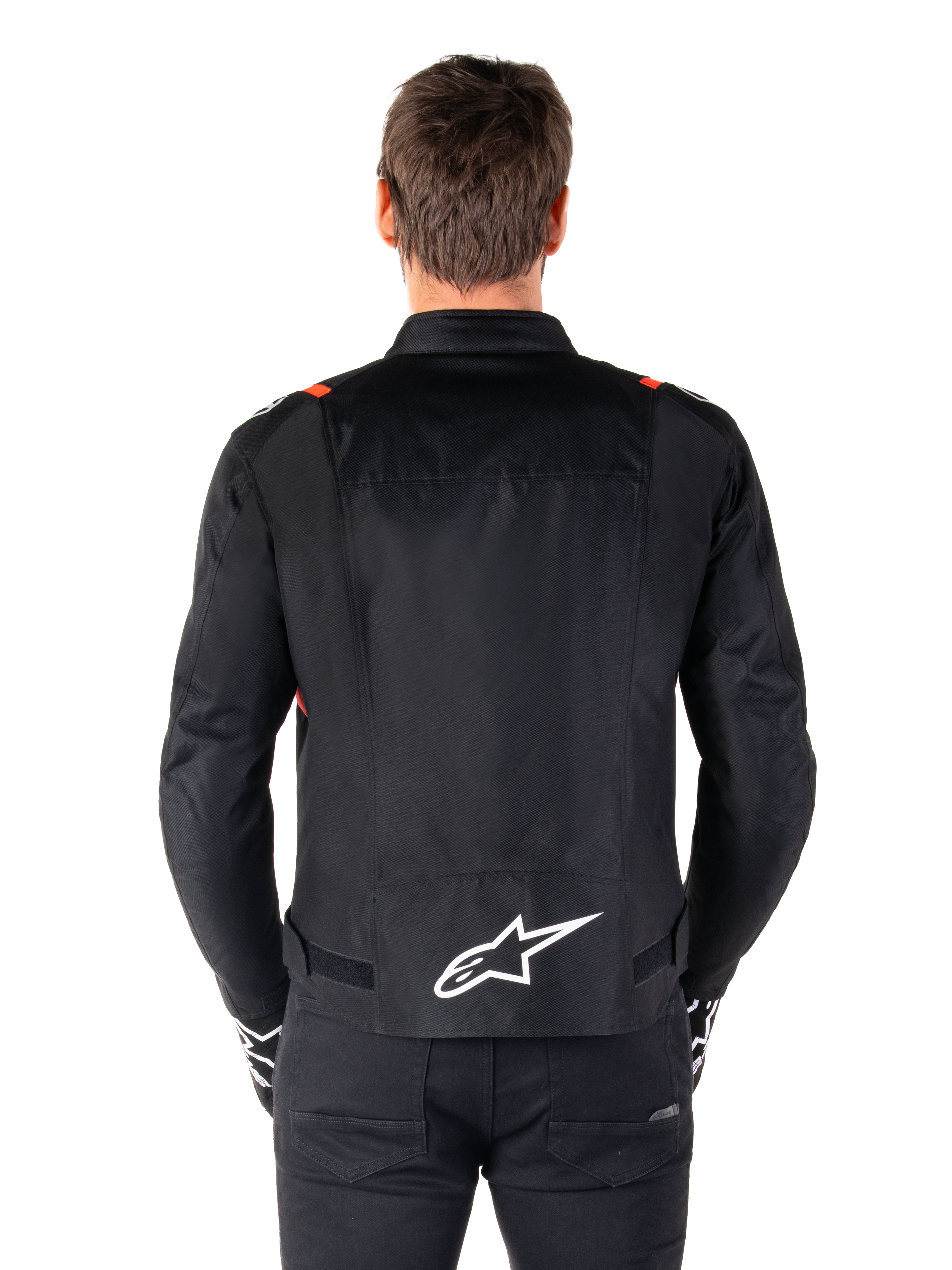 Alpinestars T-SPS V2 Waterproof-jacka, svart med vita och röd-fluo-detaljer, vy bakifrån med en stor vit Alpinestars-logotyp på nedre ryggen, sportig textiljacka för motorcykel, bärs med svarta byxor och handskar