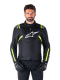 Alpinestars T-SPS V2 Waterproof Jacket, motorcykeljacka, svart med vita och neongula detaljer, bärs av en modell med svarta handskar, vit stjärnlogotyp på bröstet och neongula ränder på ärmar och axlar, sportig textilutrustning för körning i alla väder