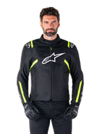 Alpinestars T-SPS V2 Waterproof Jacket, motorcykeljacka, svart med vita och neongula detaljer, bärs av en modell med svarta handskar, vit stjärnlogotyp på bröstet och neongula ränder på ärmar och axlar, sportig textilutrustning för körning i alla väder