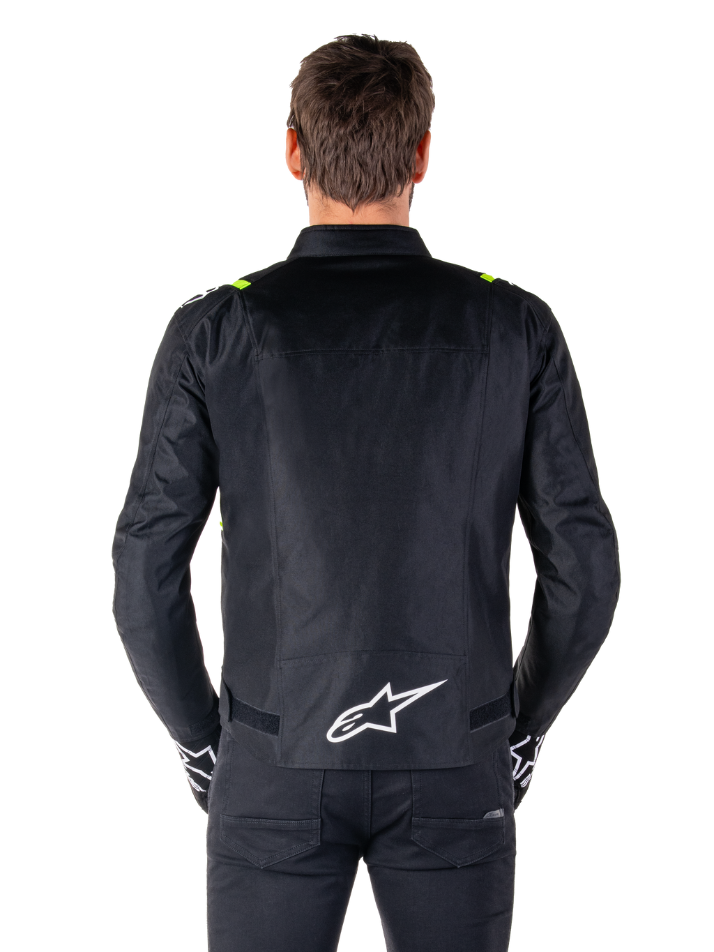 Alpinestars T-SPS V2 Waterproof Jacket, sedd bakifrån, svart med gula fluo-detaljer på axlarna och vit stjärnlogotyp på nedre delen av ryggen, textiljacka för motorcykel med sportig silhuett, bärs av en manlig modell.