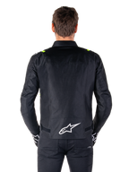 Alpinestars T-SPS V2 Waterproof Jacket, sedd bakifrån, svart med gula fluo-detaljer på axlarna och vit stjärnlogotyp på nedre delen av ryggen, textiljacka för motorcykel med sportig silhuett, bärs av en manlig modell.
