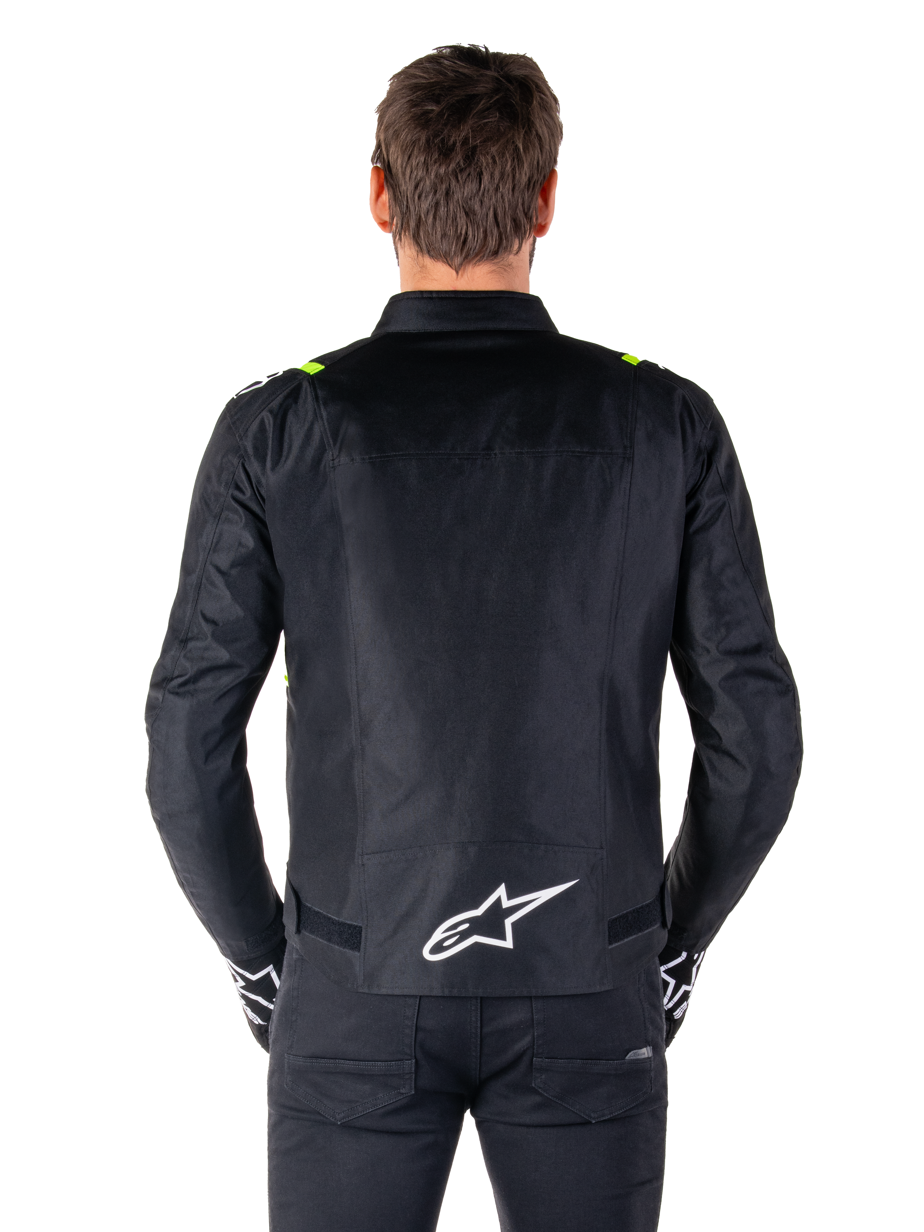 Alpinestars T-SPS V2 Waterproof Jacket, sedd bakifrån, svart med gula fluo-detaljer på axlarna och vit stjärnlogotyp på nedre delen av ryggen, textiljacka för motorcykel med sportig silhuett, bärs av en manlig modell.