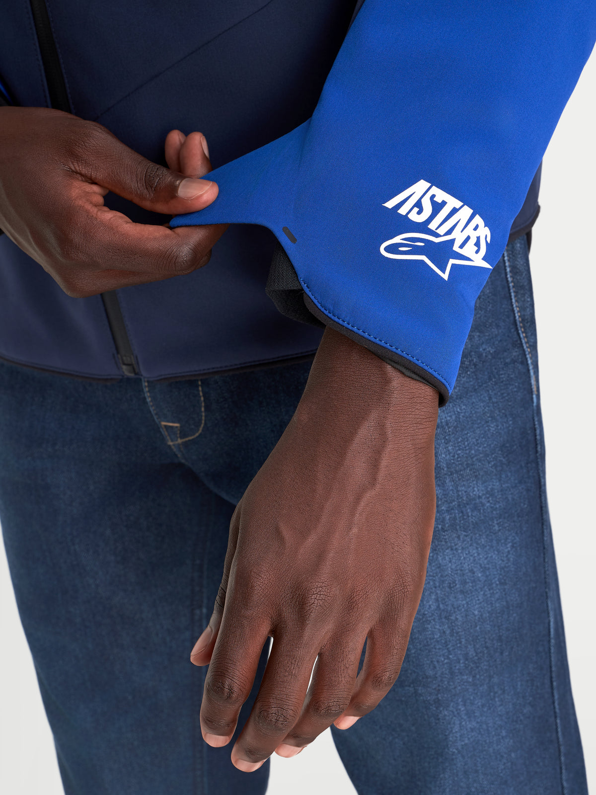 Alpinestars Aeroshell Wp jacka, närbild av ärmmuddens detalj med A-stars-logotyp, nattmarinblå och klarblå, vattentät MC-jacka för herr