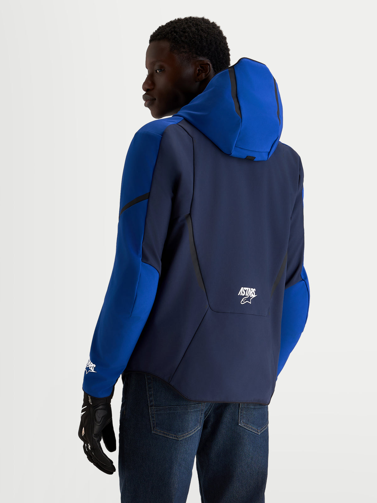 Alpinestars Aeroshell WP jacka, mörkblå och klarblå motorcykeljacka i softshell med huva för herrar, vy bakifrån på modell som bär MC-handskar