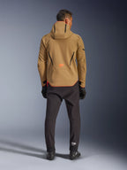 Alpinestars Aeroshell Waterproof Jacket in Dark Khaki Black Orange Fluo, back view of a man wearing the hooded softshell jacket, featuring black piping and orange logo, paired with black technical pants and gloves.