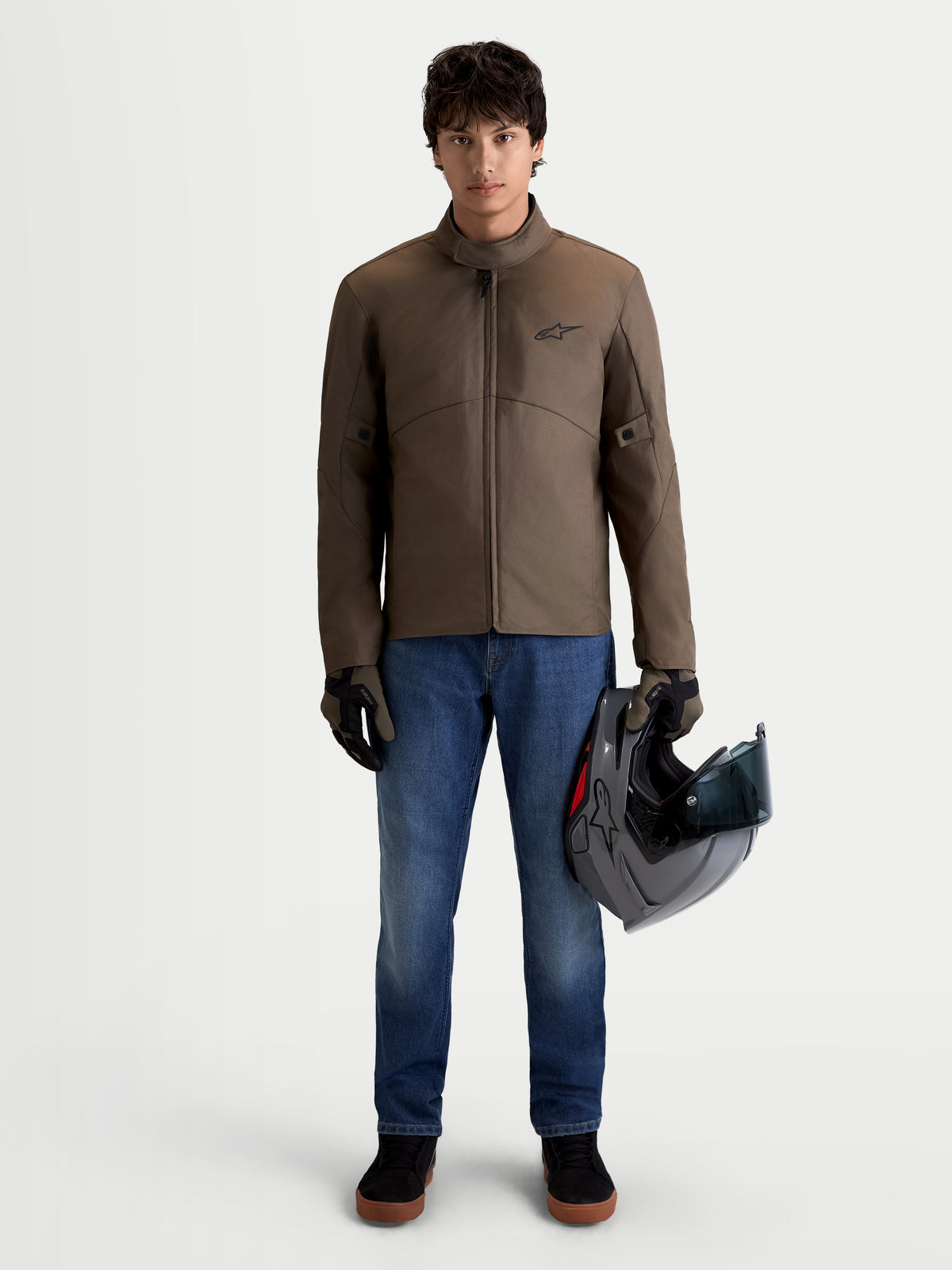 Alpinestars C-1 Waterproof Jacka, urban samtida motorcykeljacka i textilmateriell i valnötsbrun och svart, framifrån på manlig modell som bär jackan och håller en hjälm, vattentät körklädsel för alla väder