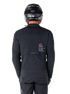 Alpinestars AMT-8 Stretch Drystar® XF-jacka, vy bakifrån, svart, bärs med svart hjälm och byxor, med Alpinestars Motion Technology-logotyp på ryggen, adventure touring-design med ergonomiskt stretchmaterial.