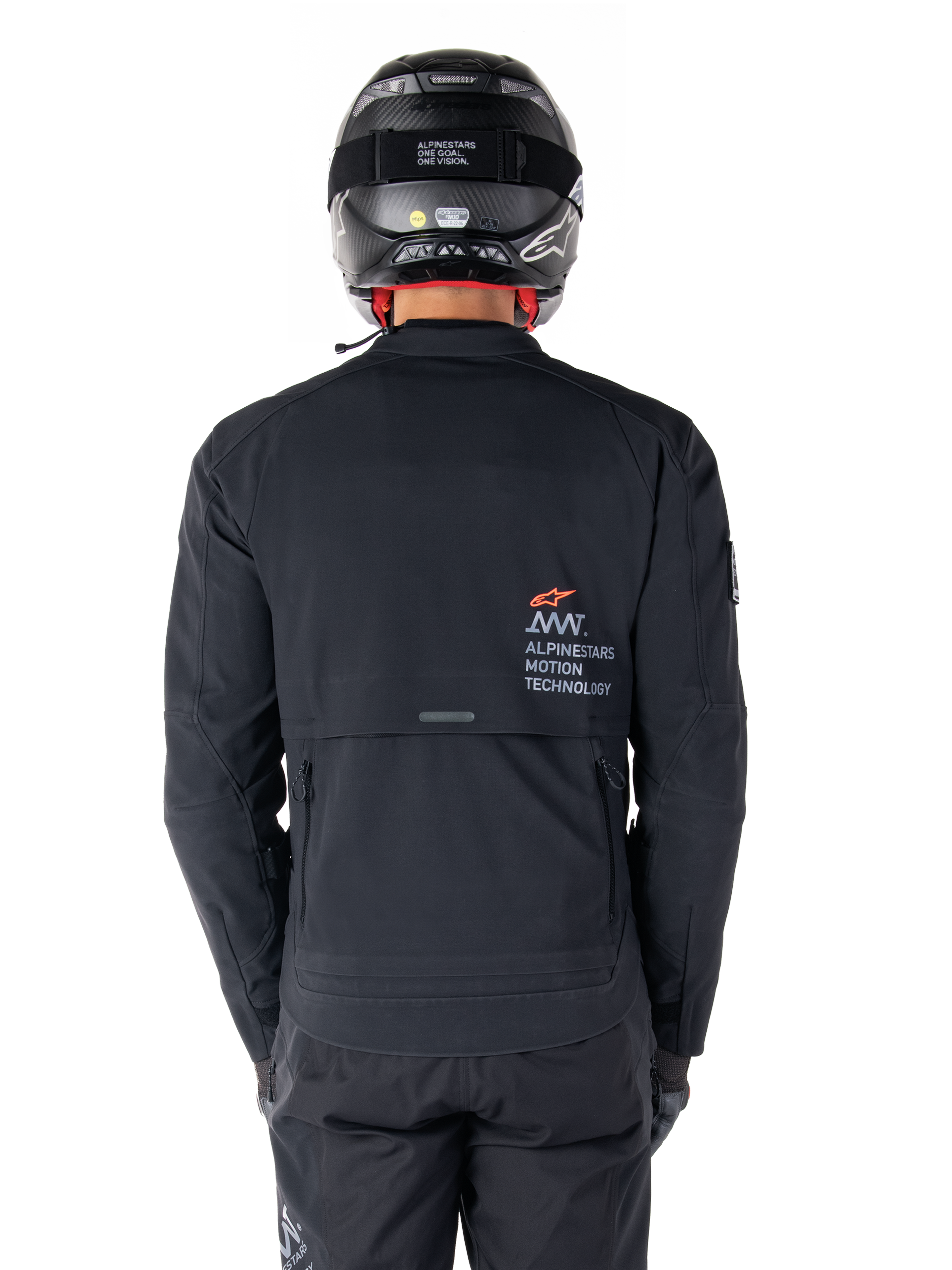 Alpinestars AMT-8 Stretch Drystar® XF-jacka, vy bakifrån, svart, bärs med svart hjälm och byxor, med Alpinestars Motion Technology-logotyp på ryggen, adventure touring-design med ergonomiskt stretchmaterial.