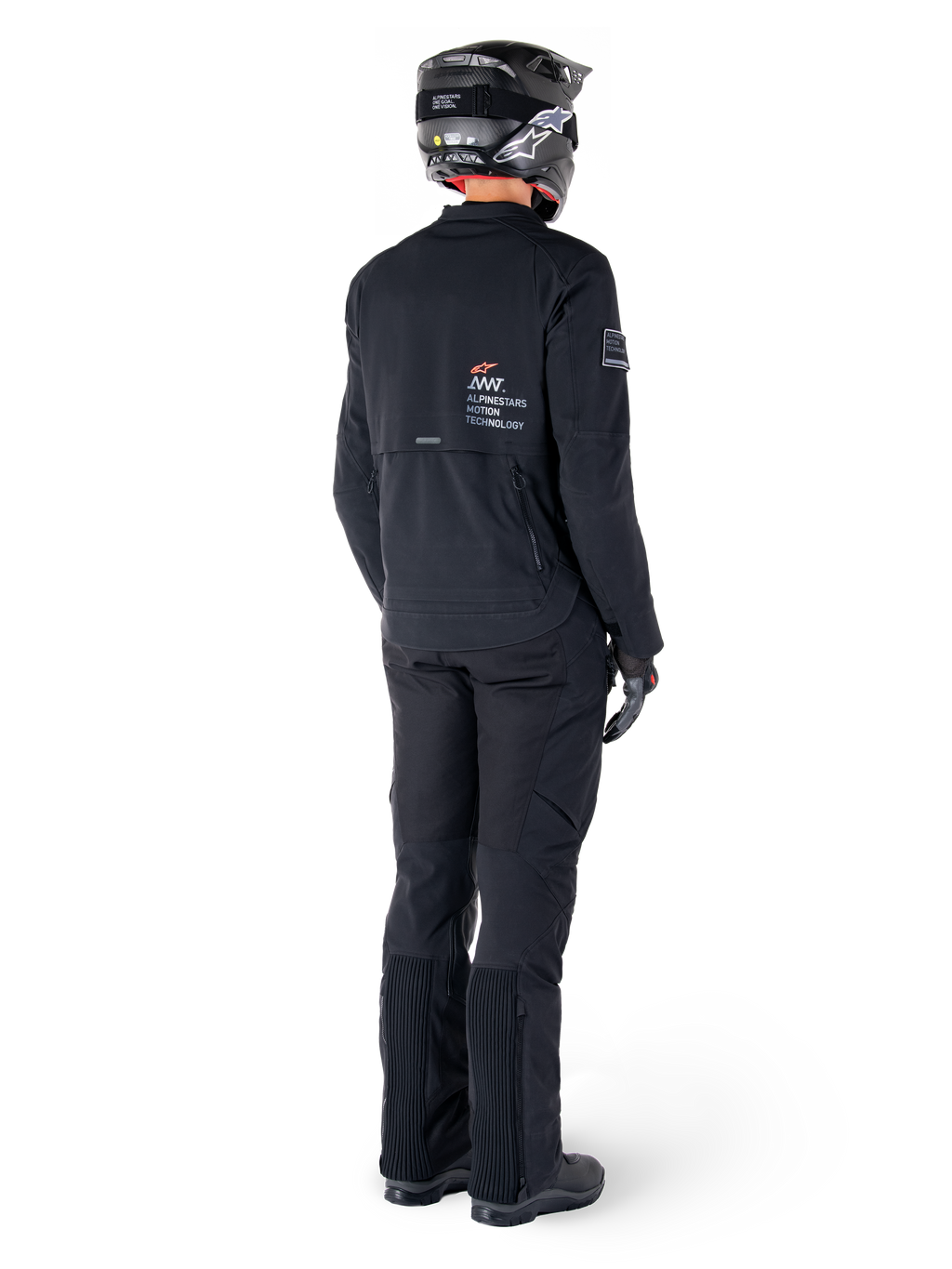 Alpinestars AMT-8 Stretch Drystar® XF-jacka, svart, vy bakifrån av en förare som bär jackan med matchande svarta byxor och en svart hjälm, med 'Alpinestars Motion Technology'-logotyp på ryggen, tekniskt stretchmaterial för äventyrsmotorcykelkörning