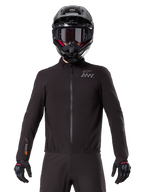 Alpinestars AMT-8 Stretch Drystar® XF-foder, svart vattentätt motorcykelfoder, med dragkedja fram och elastisk midja, AMT-logotyp på bröstet och Drystar XF-logotyp på ärmen, bärs med en svart hjälm och handskar.