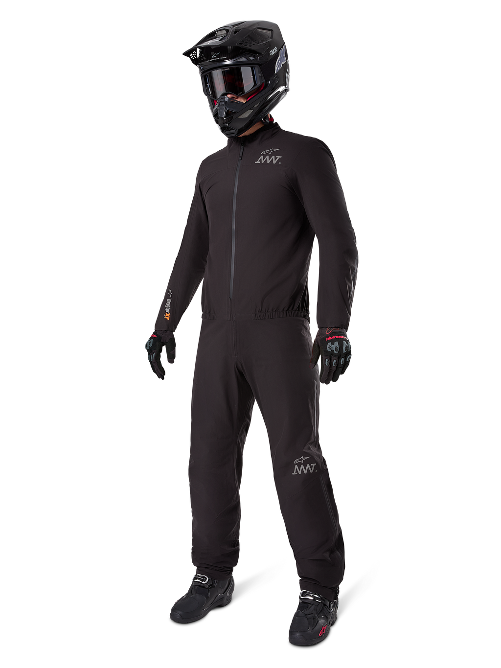 Alpinestars AMT-8 Stretch Drystar® XF-foder, svart vattentätt motorcykelställ, bärs med svart hjälm, goggles och handskar, med AMT- och Drystar XF-logotyper, funktionell äventyrsutrustning för skydd i alla väder.