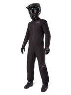 Alpinestars AMT-8 Stretch Drystar® XF-foder, svart vattentätt motorcykelställ, bärs med svart hjälm, goggles och handskar, med AMT- och Drystar XF-logotyper, funktionell äventyrsutrustning för skydd i alla väder.