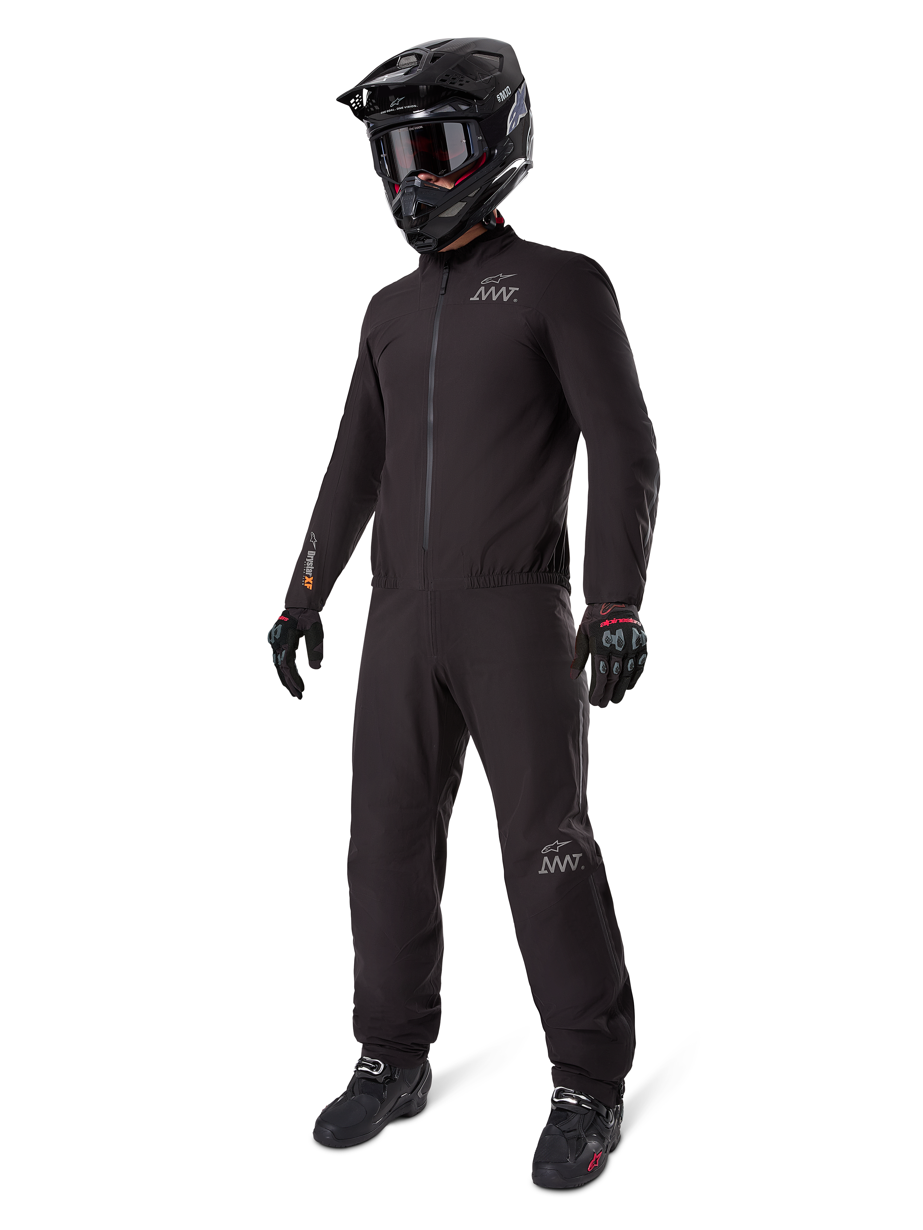 Alpinestars AMT-8 Stretch Drystar® XF-foder, svart vattentätt motorcykelställ, bärs med svart hjälm, goggles och handskar, med AMT- och Drystar XF-logotyper, funktionell äventyrsutrustning för skydd i alla väder.