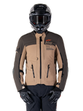 Alpinestars AMT-8 Stretch Drystar XF-jacka, motorcykeljacka för adventure touring, mörkkaki och mörkbrun, med orange Astars-logotyp och svarta dragkedjor, bärs med svart adventure-hjälm och handskar, komplett körutrustning
