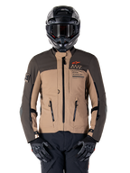 Alpinestars AMT-8 Stretch Drystar XF-jacka, motorcykeljacka för adventure touring, mörkkaki och mörkbrun, med orange Astars-logotyp och svarta dragkedjor, bärs med svart adventure-hjälm och handskar, komplett körutrustning