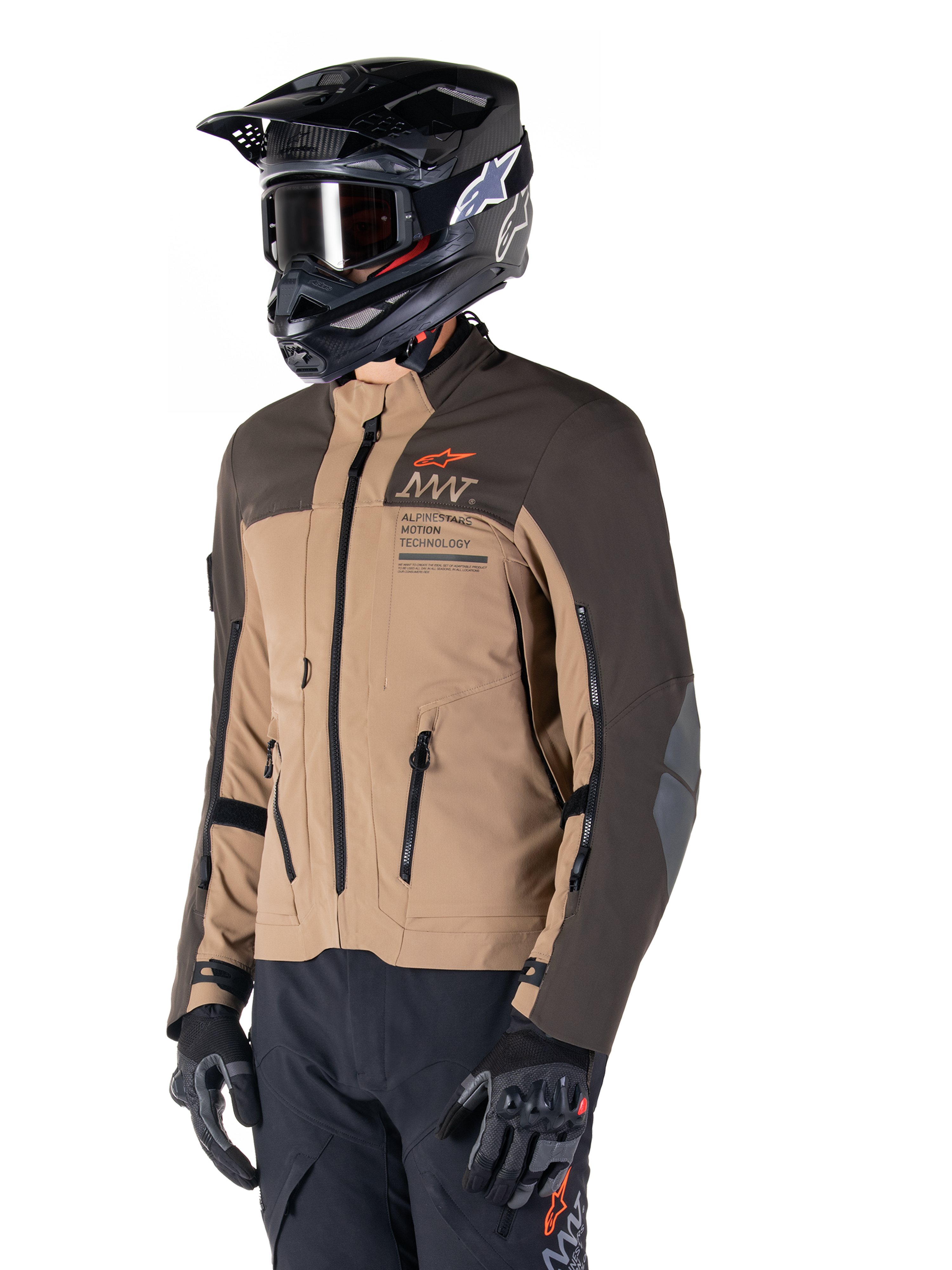 Alpinestars AMT-8 Stretch Drystar® XF jacka, äventyrsmotorcykeljacka, mörkbrun och mörk khaki, bärs med en svart terränghjälm och goggles, med Alpinestars Motion Technology-logotyp och ventilationsöppningar med dragkedja.