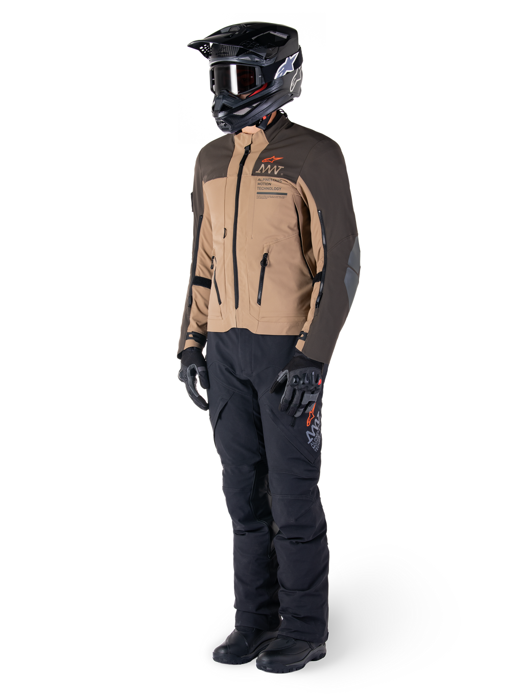 Äventyrsförare i komplett utrustning, Alpinestars AMT-8 Stretch Drystar® XF-jacka i mörkbrunt och mörk khaki, kombinerad med svarta äventyrsbyxor, svart hjälm, handskar och stövlar, med orange AMT-branding och tekniska ventilationsdragkedjor för långdistanstouring