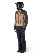 Äventyrsförare i komplett utrustning, Alpinestars AMT-8 Stretch Drystar® XF-jacka i mörkbrunt och mörk khaki, kombinerad med svarta äventyrsbyxor, svart hjälm, handskar och stövlar, med orange AMT-branding och tekniska ventilationsdragkedjor för långdistanstouring
