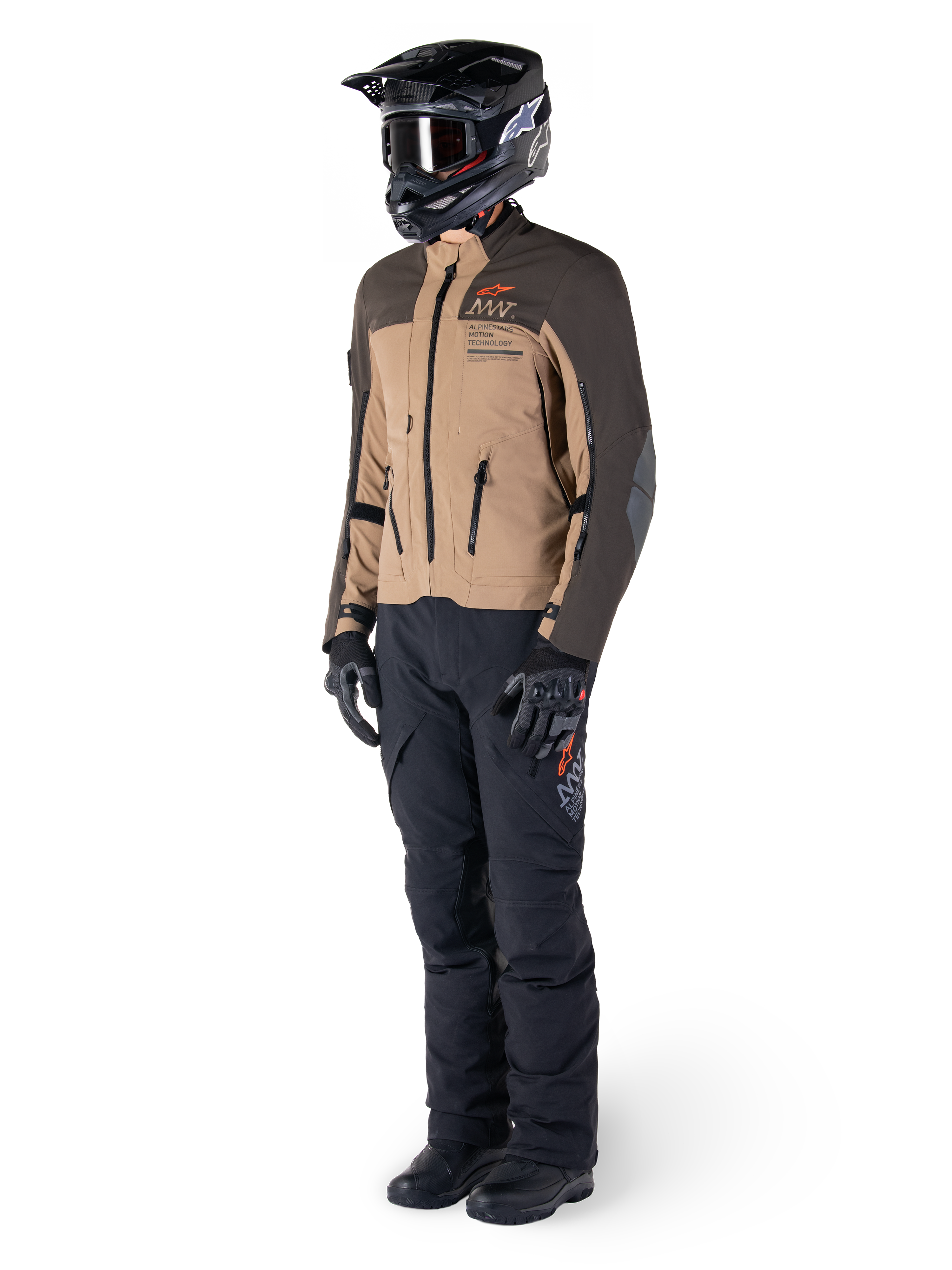 Äventyrsförare i komplett utrustning, Alpinestars AMT-8 Stretch Drystar® XF-jacka i mörkbrunt och mörk khaki, kombinerad med svarta äventyrsbyxor, svart hjälm, handskar och stövlar, med orange AMT-branding och tekniska ventilationsdragkedjor för långdistanstouring