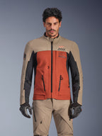 Alpinestars AMT-8 Stretch Drystar® XF-jacka, Walnut Rust Black adventure touring-jacka, bärs av en manlig modell med matchande byxor och handskar, trefärgad design i beige, rostbrunt och svart med AMT-logotyp på bröstet, aktiv touring-passform för motorcykelkörning