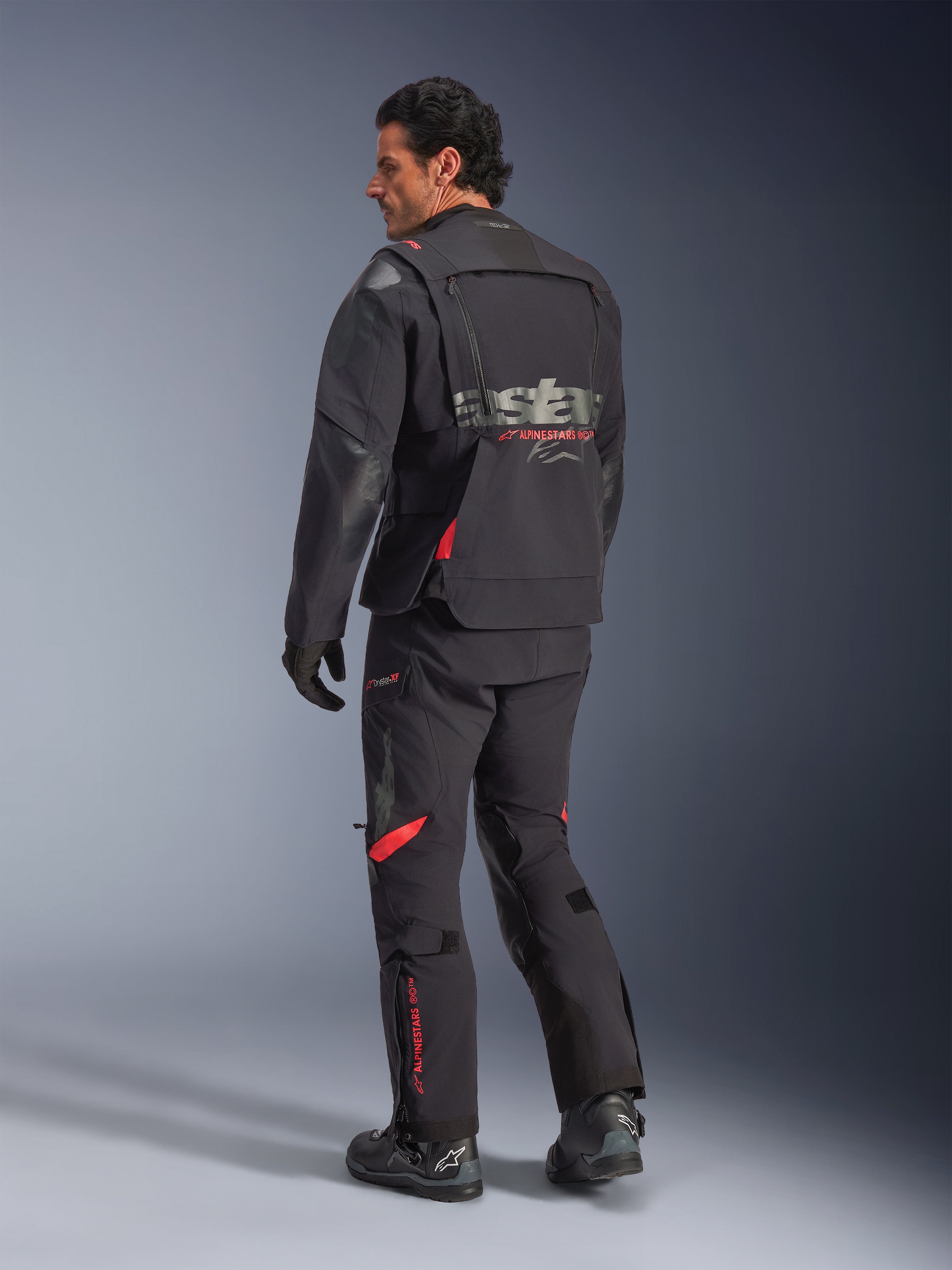 Alpinestars Halo Pro Drystar® XF laminerad jacka, äventyrsjacka för motorcykel, Black Dark Shadow med röda detaljer, vy bakifrån buren med matchande byxor och stövlar, med grå logotyp på ryggen, modulär textilkonstruktion för äventyrskörning