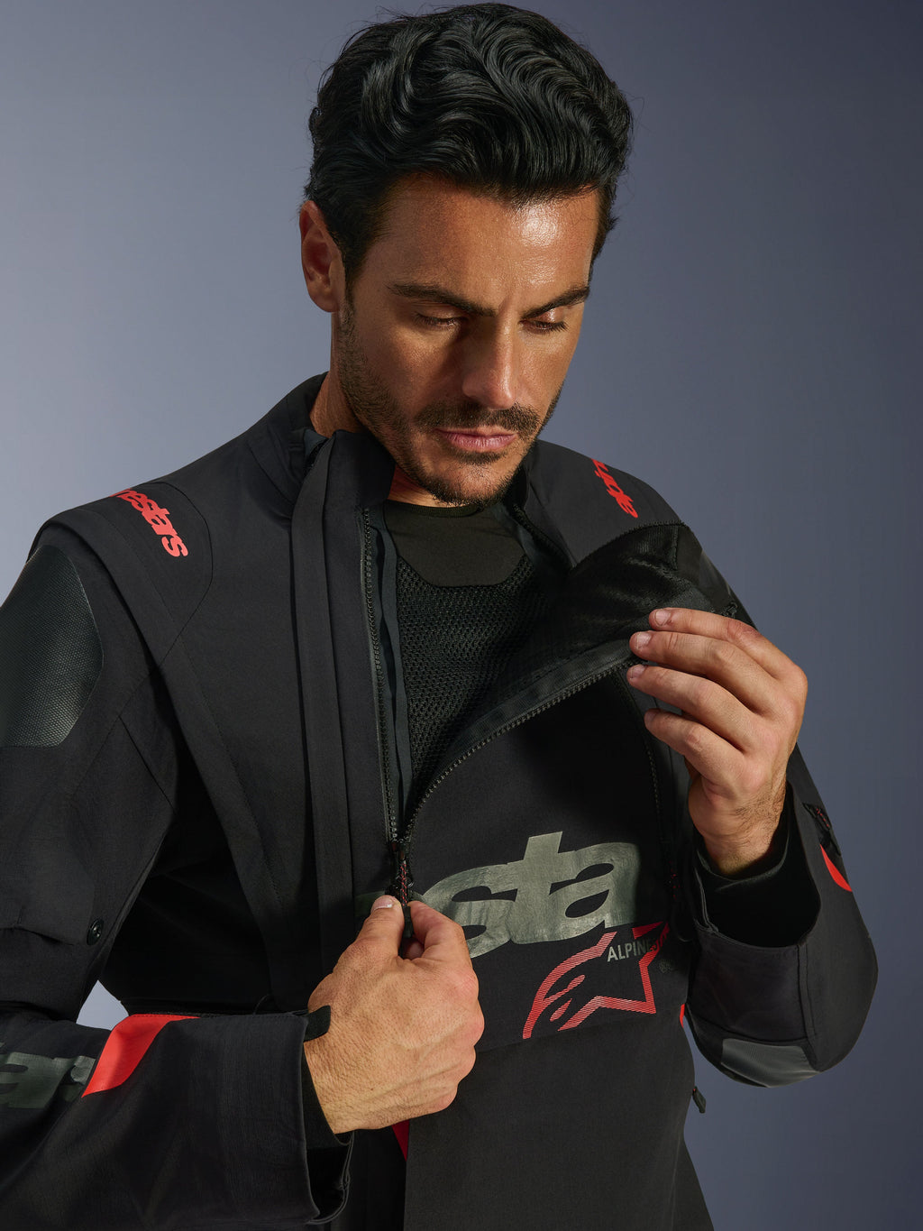 Alpinestars Halo Pro Drystar® XF laminerad jacka, Black Dark Shadow, modell som demonstrerar det modulära ventilationssystemet genom att öppna den asymmetriska bröstpanelen, adventure touring-jacka med röda Alpinestars-logotyper och tekniska meshdetaljer.