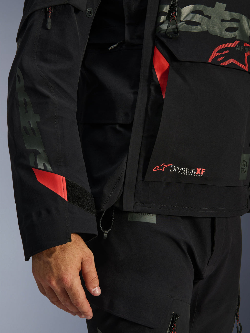 Alpinestars Halo Pro Drystar® XF laminerad jacka, motorcykeljacka, svart med röda detaljer, närbild som visar Drystar® XF-märkning, teknisk laminerad skaltextur och justerbara ärmdetaljer för äventyrskörning