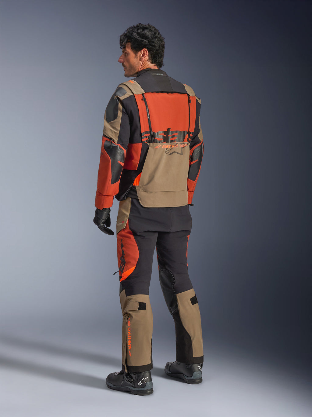 Alpinestars Halo Pro Drystar® XF laminerad jacka, Walnut Rust Black äventyrsmotorcykeljacka, vy bakifrån bärs med matchande byxor och svarta stövlar, med tekniskt 3L-stretchmaterial, modulära ventilationspaneler och orange logotyp på ryggen