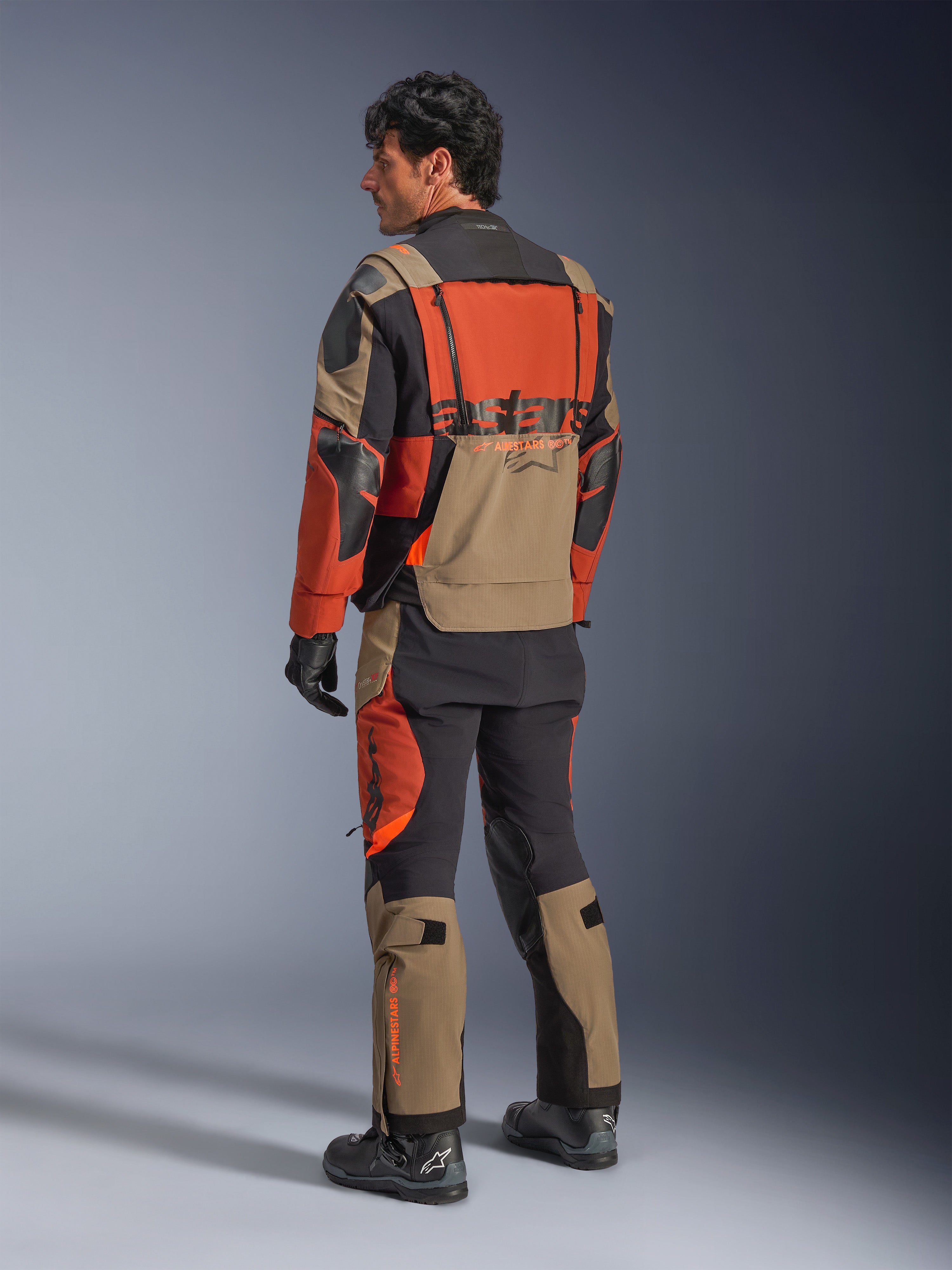 Alpinestars Halo Pro Drystar® XF laminerad jacka, Walnut Rust Black äventyrsmotorcykeljacka, vy bakifrån bärs med matchande byxor och svarta stövlar, med tekniskt 3L-stretchmaterial, modulära ventilationspaneler och orange logotyp på ryggen