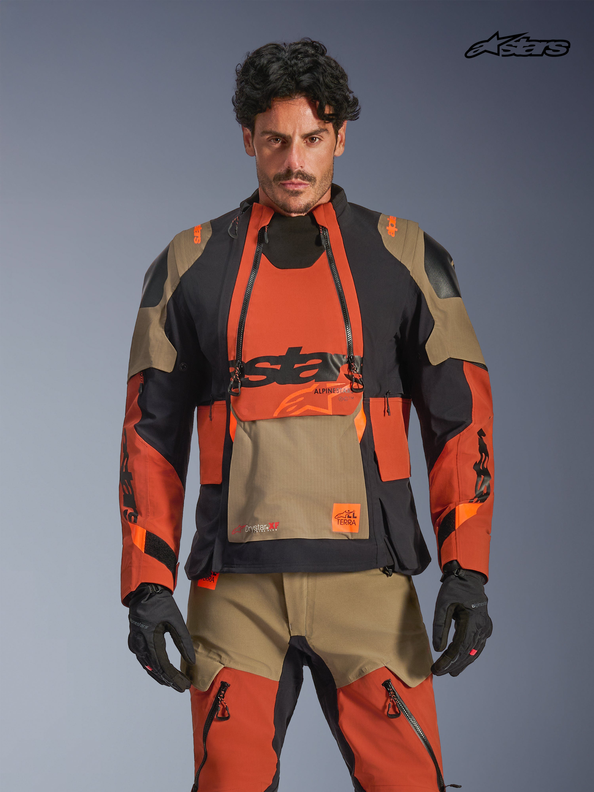 Alpinestars Halo Pro Drystar XF laminatjacka, äventyrsmotorcykeljacka för herr i valnötsbrun, rostorange och svart, framifrån på modell som bär matchande utrustning, med vattentät textilkonstruktion och modulära ventilationspaneler