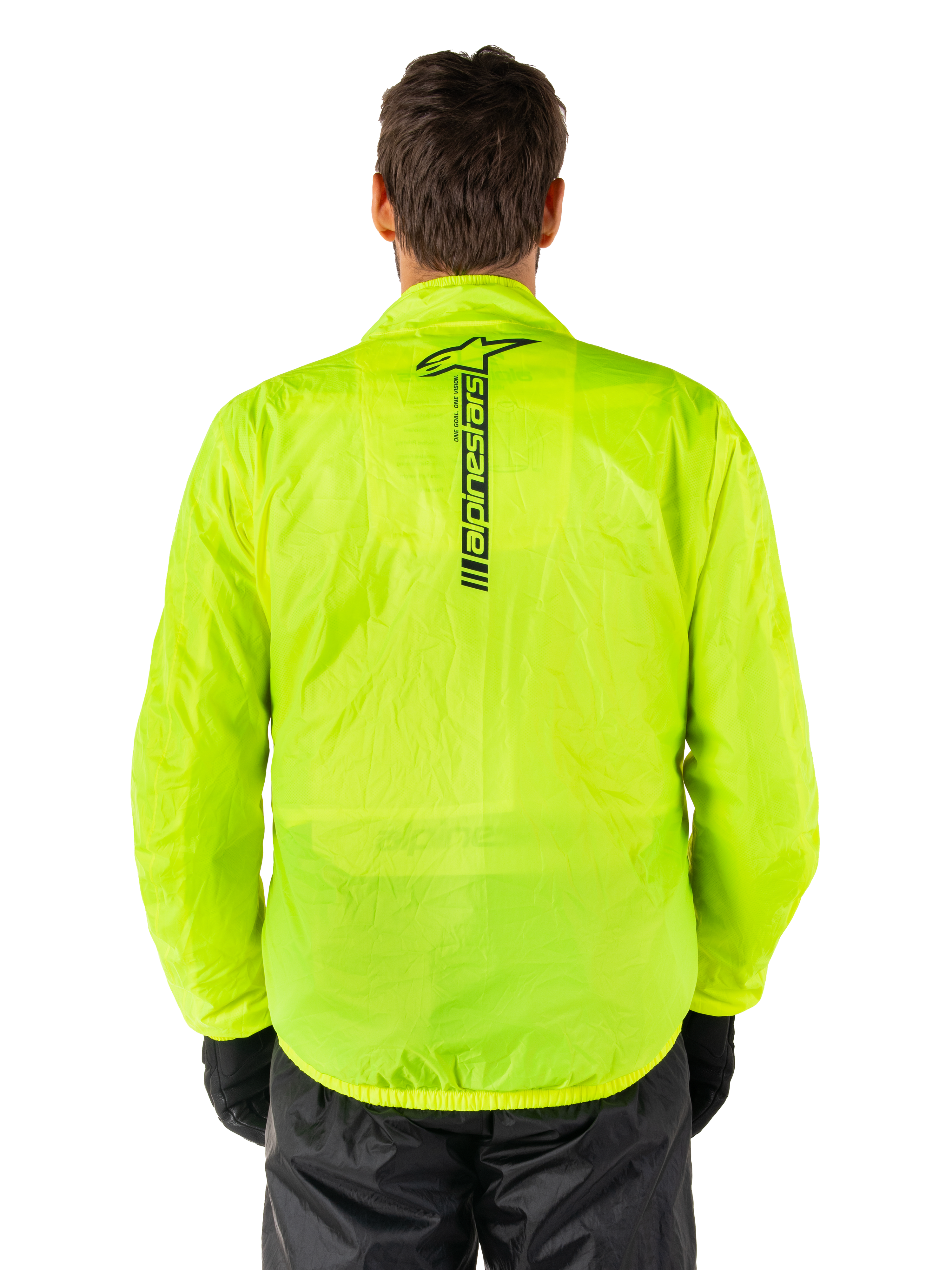 Alpinestars Hurricane Rain V2-jacka, regnjacka för motorcykel, Yellow Fluo, vy bakifrån som visar en vertikal svart Alpinestars-logotyp mitt på ryggen, lätt vattentätt material, bärs med svarta körbyxor och handskar