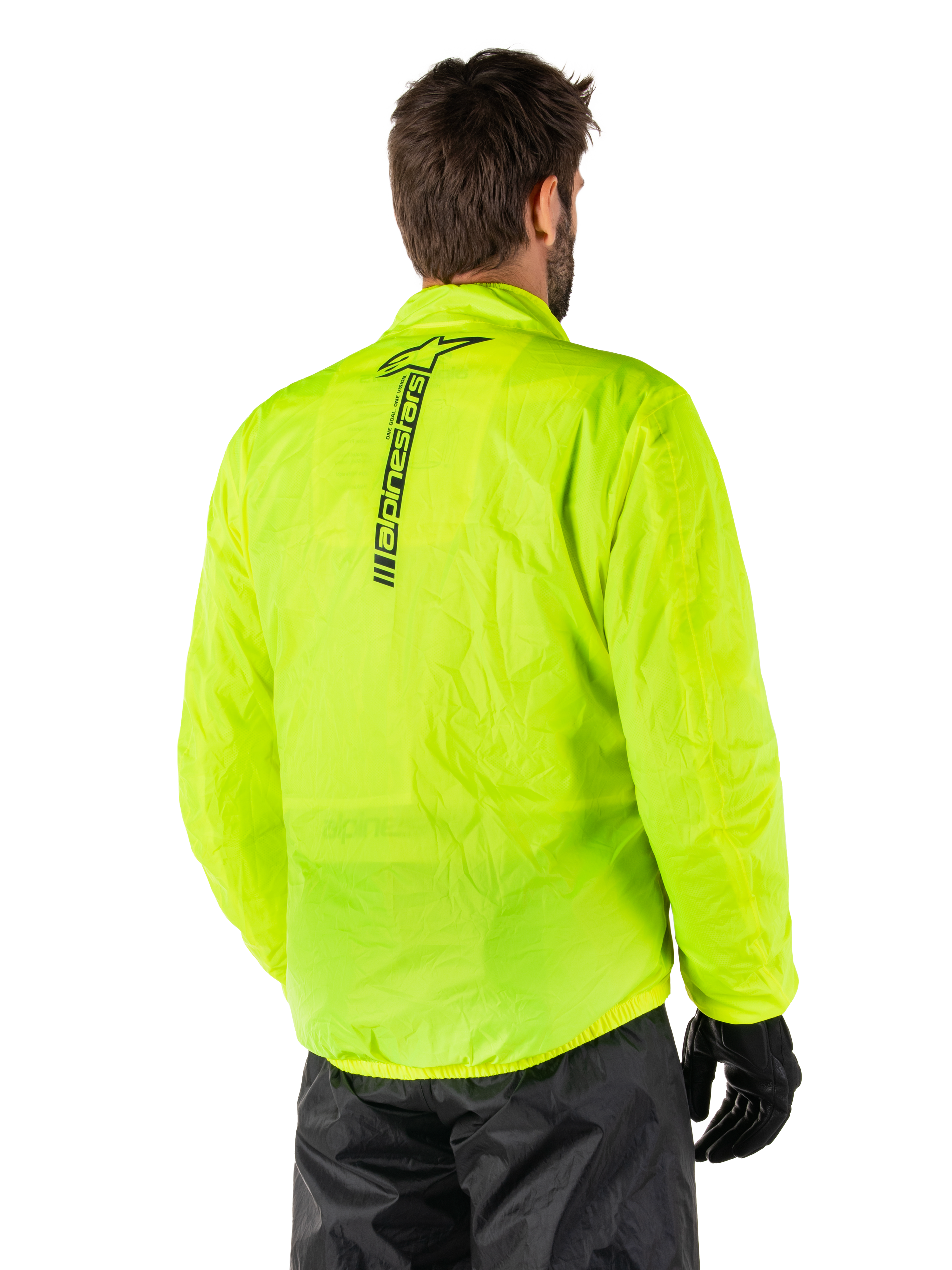 Alpinestars Hurricane Rain V2-jacka, gul fluo, ryggvy buren av manlig modell, med vertikalt svart Alpinestars-ordmärke mitt på ryggen, elastisk midja och ärmslut, vattentät och packbar design