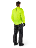 Person bakifrån som bär Alpinestars Hurricane Rain V2 Jacket i Yellow Fluo och Hurricane Rain V2 Pant i Black, vertikal logotyp på jackans rygg, vattentät motorcykelregnutrustning med svarta handskar och stövlar