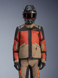 Alpinestars Andes V4 Drystar®-jacka, äventyrsjacka för motorcykel, Walnut Rust Black, bärs med matchande hjälm och handskar, teknisk design i flera paneler i beige, rödorange och svart med synlig orange logotyp och vattentäta dragkedjor.
