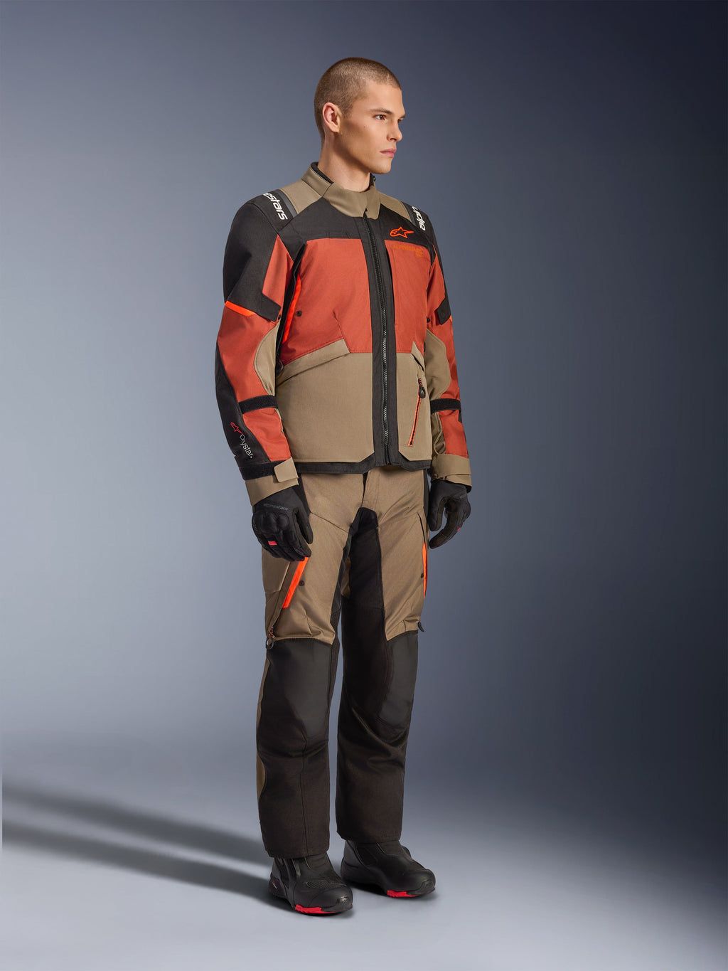 Alpinestars Andes V4 Drystar® jacka, adventure touring-jacka, Walnut Rust Black, bärs med matchande byxor och svarta stövlar, färgblockerad design i beige, rostbrunt och svart, slitstark textilkonstruktion med synliga dragkedjor och Alpinestars-logotyper.