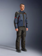 Manlig modell som bär Alpinestars Andes V4 Drystar®-jacka i Night Navy och Mood Indigo med svarta paneler och röda detaljer, kombinerat med svarta motorcykelbyxor och stövlar, teknisk adventure touring-utrustning i studiomiljö.