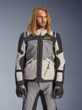 Alpinestars Andes V4 Drystar-jacka, äventyrs- och touringjacka för motorcykel, mörkgrå och isgrå med neongula detaljer, bärs av en modell med matchande byxor och handskar, textilkonstruktion med flera fickor för körning i alla väder