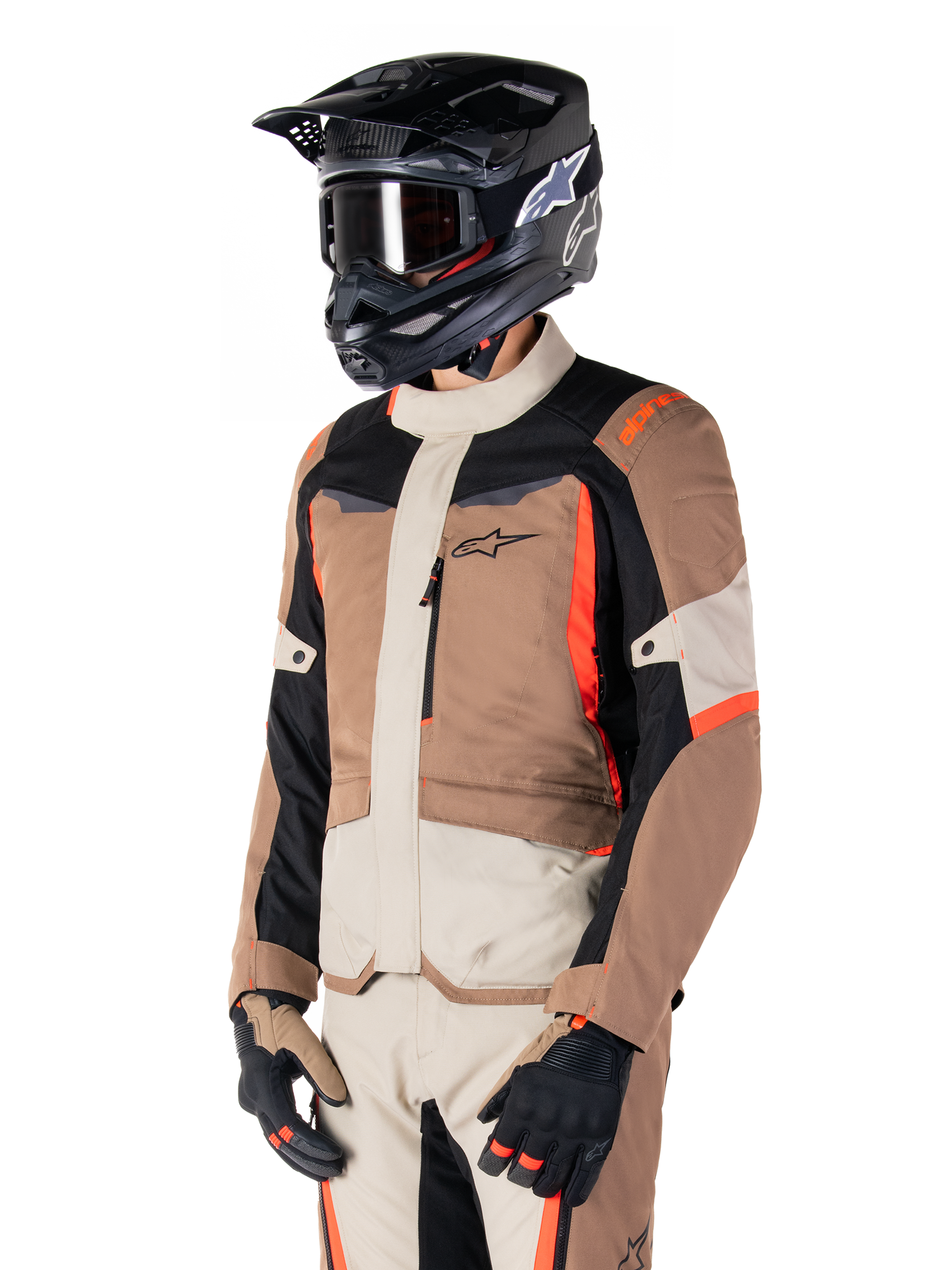 Alpinestars ST-1 Waterproof Jacket, adventure touring-jacka, mörk khaki, sand, svart och fluorescerande röd, bärs av en förare med svart motocrosshjälm och goggles, flerpanelsdesign med lastfickor och Alpinestars logotyp på bröstet