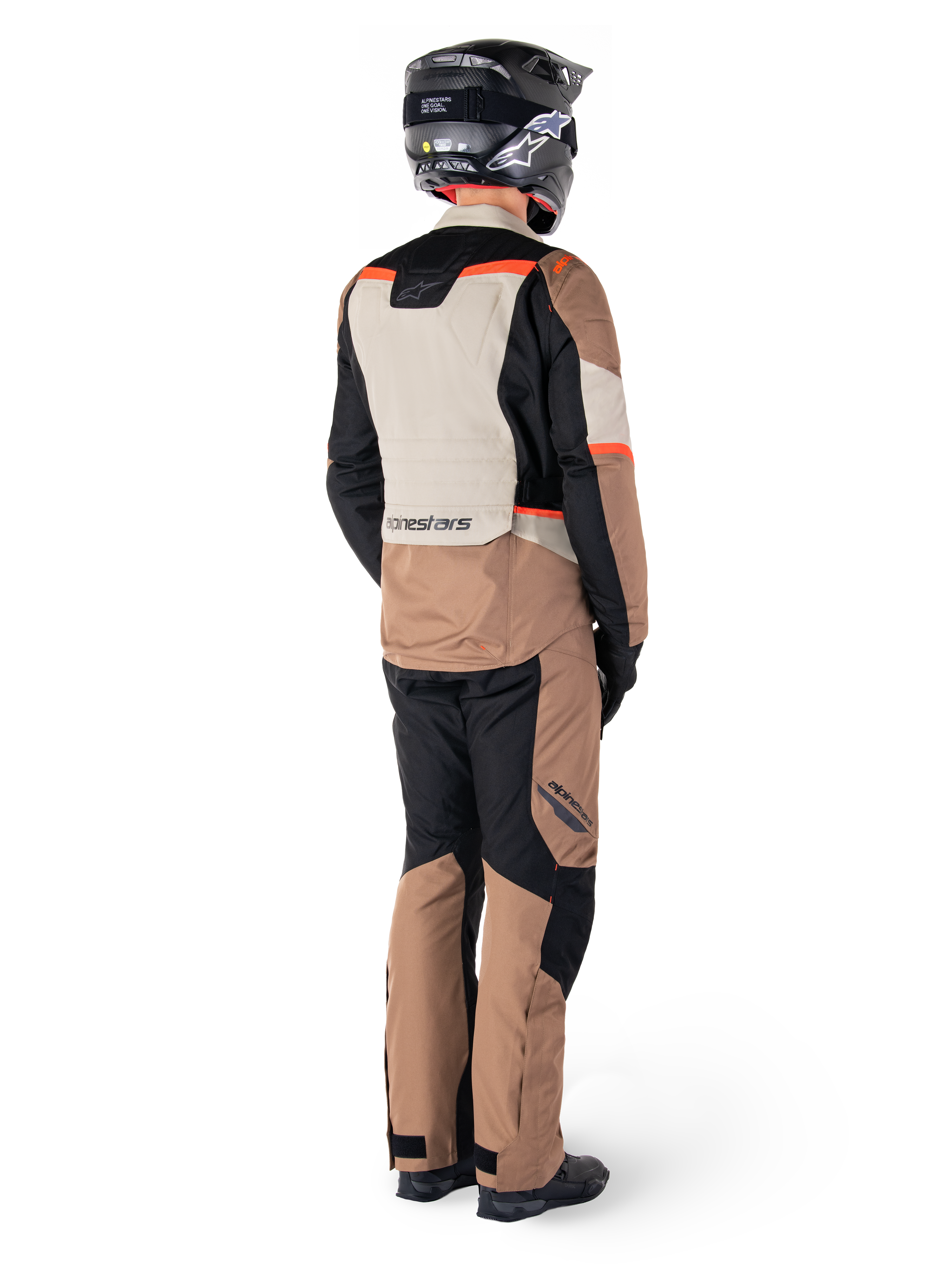 Alpinestars ST-1 Waterproof-jacka, äventyrstouringjacka, mörk khaki, sand, svart och röd fluo, vy bakifrån buren med matchande byxor och svart hjälm, med färgblockerade paneler och fluorescerande röda detaljer.
