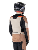 Alpinestars ST-1 Waterproof Jacket, adventure touring-jacka, Dark Khaki Sand Black Red Fluo, ryggvy som visar färgblockerade textilpaneler, fluorescerande röda detaljer och Alpinestars-logotyp på nedre ryggen, bärs av en förare med svart hjälm.