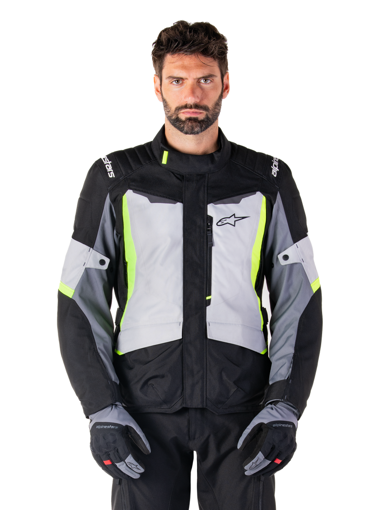 Alpinestars ST-1 Waterproof Jacket, adventure touring-motorcykeljacka, Ice Gray, svart och neongul, bärs av en man med matchande handskar och svarta byxor, neongula detaljer på bröstet och kragen, Alpinestars-logotyp på bröstet