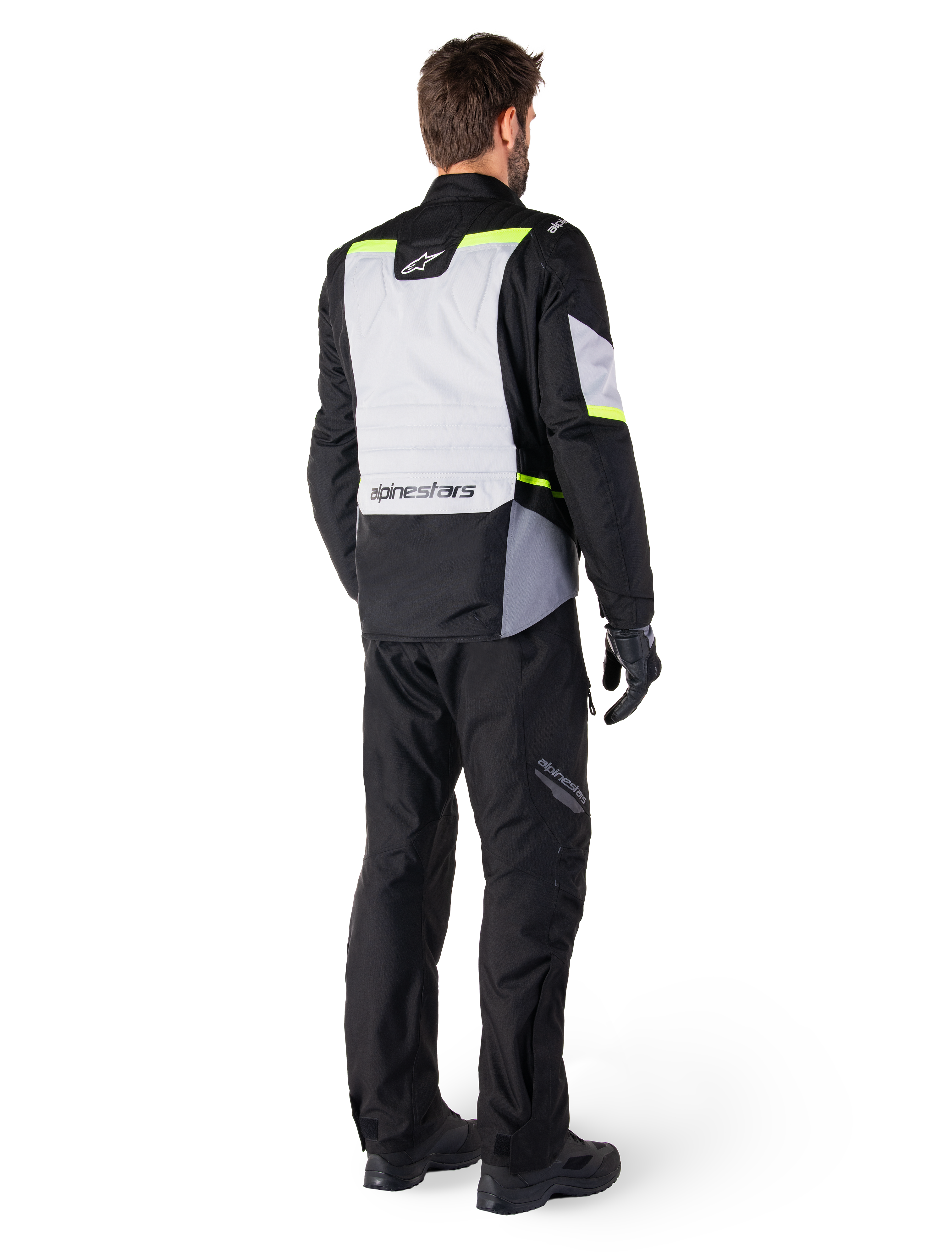 Alpinestars ST-1 Waterproof Jacket, adventure touring motorcycle jacket shown from the back, Ice Gray and Black with Yellow Fluo accents, worn with black riding pants and gloves, modern streamlined design with high-visibility fluorescent details and Alpinestars branding.
