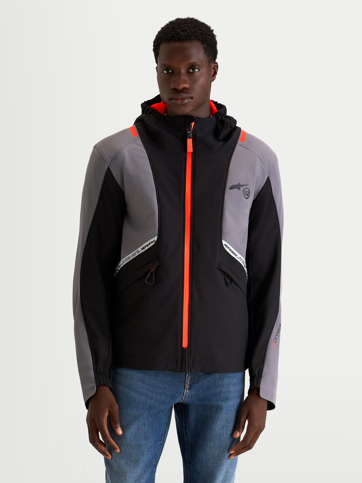 Alpinestars C-5 Drystar Jacket, men's urban contemporary motorcycle textile jacket in black and dark gray, front view on a model showing waterproof softshell construction, integrated hood, and bright orange zipper details