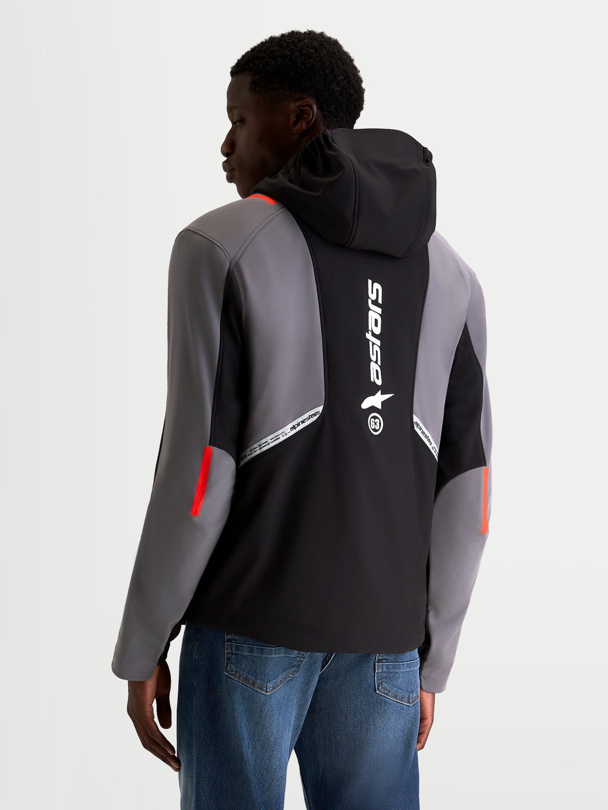 Alpinestars C 5 Drystar jacka, urban motorcykeljacka i softshell för herr, svarta och mörka grå färger, vy bakifrån på modell som visar integrerad huva, stor reflekterande Alpinestars-logotyp på baksidan och vattentät texturkonstruktion