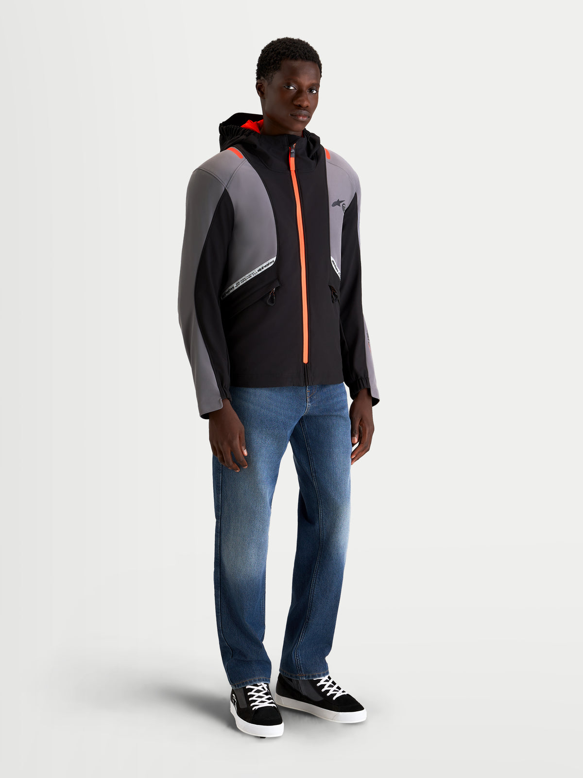 Alpinestars C-5 Drystar Jacket, men's urban contemporary motorcycle textile jacket in black and dark gray, featuring an integrated hood, waterproof construction, and bright orange zipper details worn by a model.