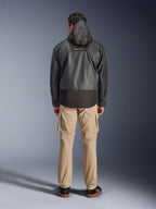 Alpinestars Mospher Waterproof Jacket, svart motorcykelparkas sedd bakifrån, med MO.ST.EQ-logotyp på övre delen av ryggen och ripstop-tyg, bärs med beige cargobyxor och svarta sneakers, urban pendlarstil.