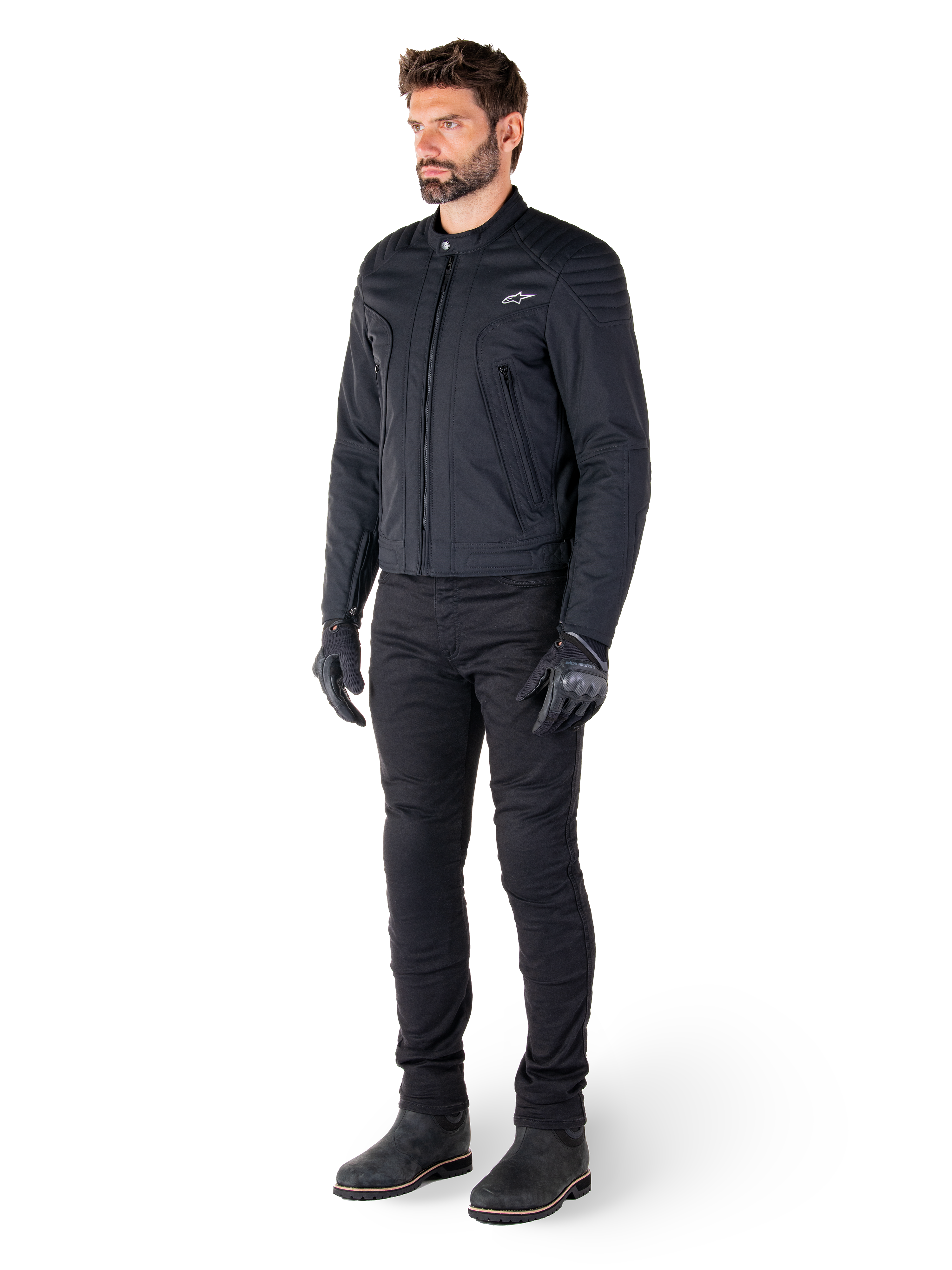 Male rider wearing the Alpinestars Clayton WR Jacket, Black urban motorcycle jacket, slim-fit design with quilted shoulder accents and matte finish, paired with black technical riding pants and gloves.