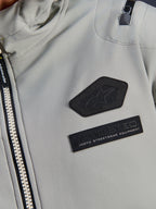 Alpinestars Moblast Waterproof Jacket, Iron Gray, close-up detail of chest patches featuring the Alpinestars logo and MO.ST.EQ. Moto Streetwear Equipment branding, technical ripstop fabric with heavy-duty front zipper and shoulder pocket detail.