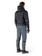 Alpinestars Mohobbs Waterproof Jacket, svart, baksida av quiltad vadderad bomberjacka med präglat vertikalt ordmärke på ryggen, stylad med grå körbyxor och svarta handskar, urban streetwear-inspirerad motorcykelutrustning