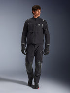 Manlig modell iklädd Alpinestars Andes Pro Drystar® XF-jacka, svart och mörkgrå äventyrsmotorcykeljacka, matchande tekniska byxor och handskar, flera fickor och 'Terra'-logotyp på bröstet.
